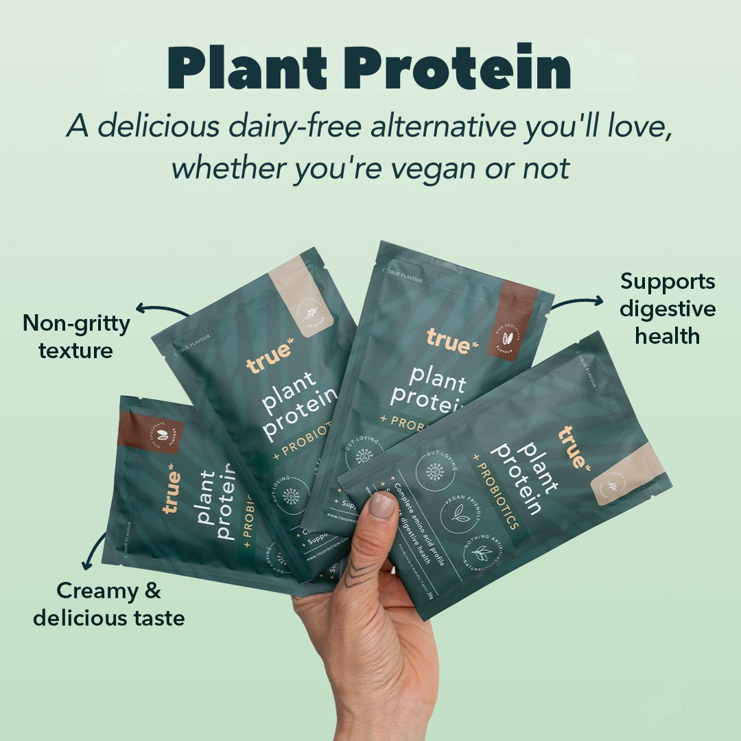 Hand holding four teal single‑serve True Plant Protein sachets - dairy‑free vegan protein powder with probiotics, non‑gritty texture, creamy taste and digestive health support, eco‑friendly packaging.