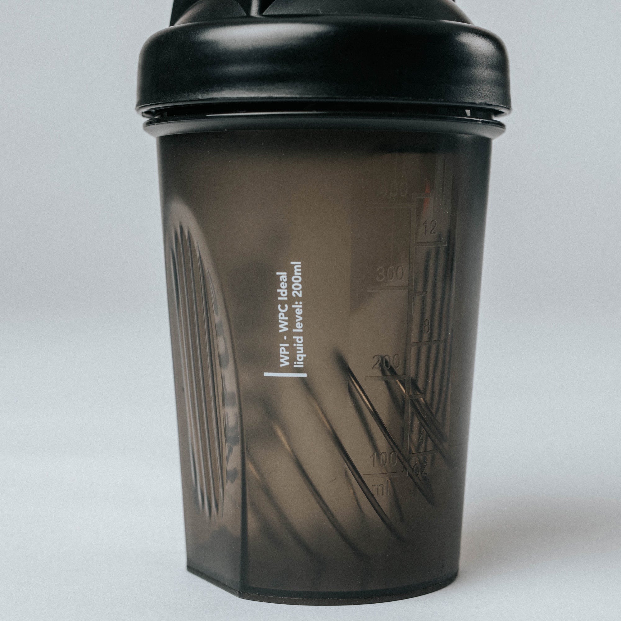 Black translucent small protein shaker bottle with black screw lid, 200–300 ml measurement markings and internal mixing grid — fitness supplement shaker cup product photo
