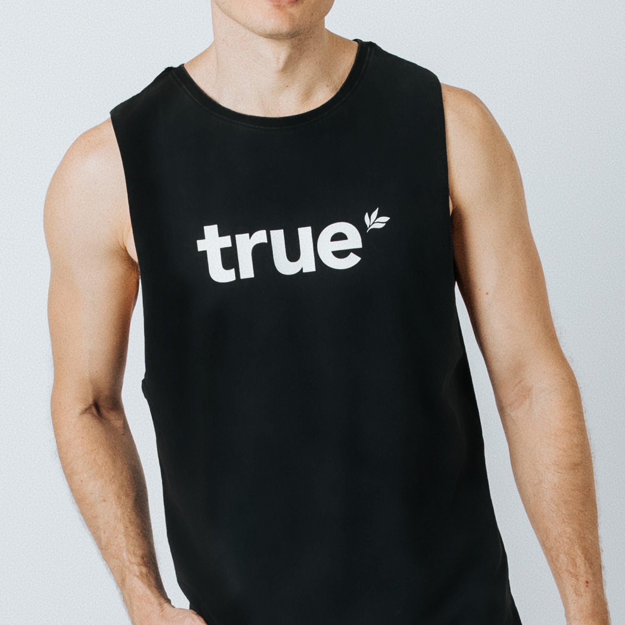 Men’s black sleeveless tank top with white “true” logo on front, modeled by fit male torso on neutral studio background — athletic casual summer top.