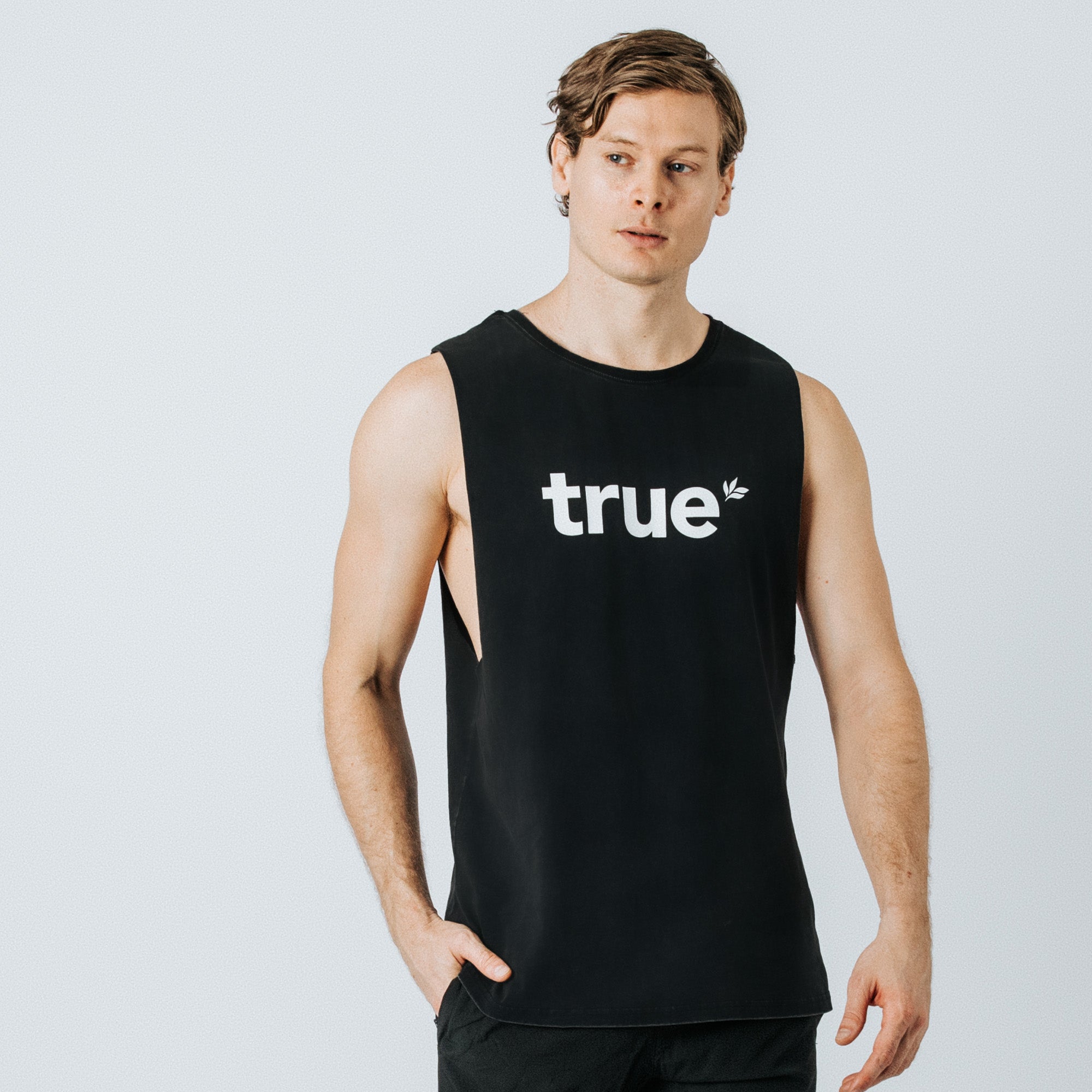 Men’s black muscle tank top with white "true" logo, sleeveless athletic fit casual workout tee on male model — studio product photo for men’s activewear.