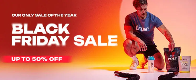 Black Friday sale banner: fitness supplements and shaker bottle from True Nutrition with PRE and POST powder packs, up to 50% off, male athlete kneeling on orange-red background, ropes and workout gear—Black Friday fitness deals.
