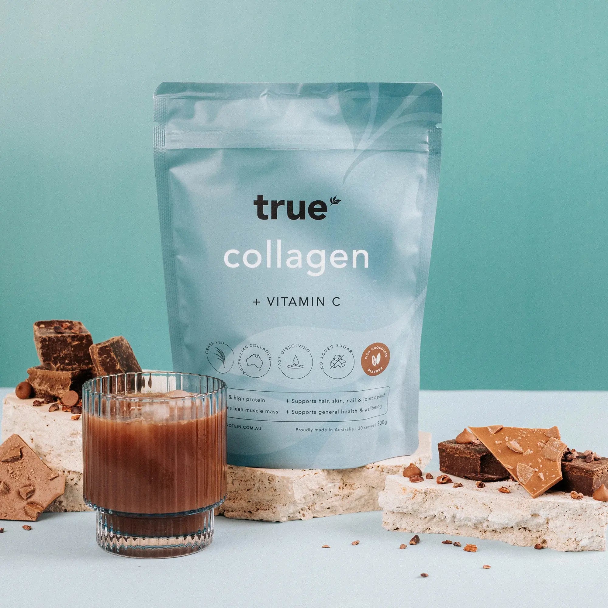 True Collagen + Vitamin C chocolate-flavoured powder pouch with chocolate pieces and a glass of prepared chocolate collagen drink on teal background — Australian-made collagen supplement.