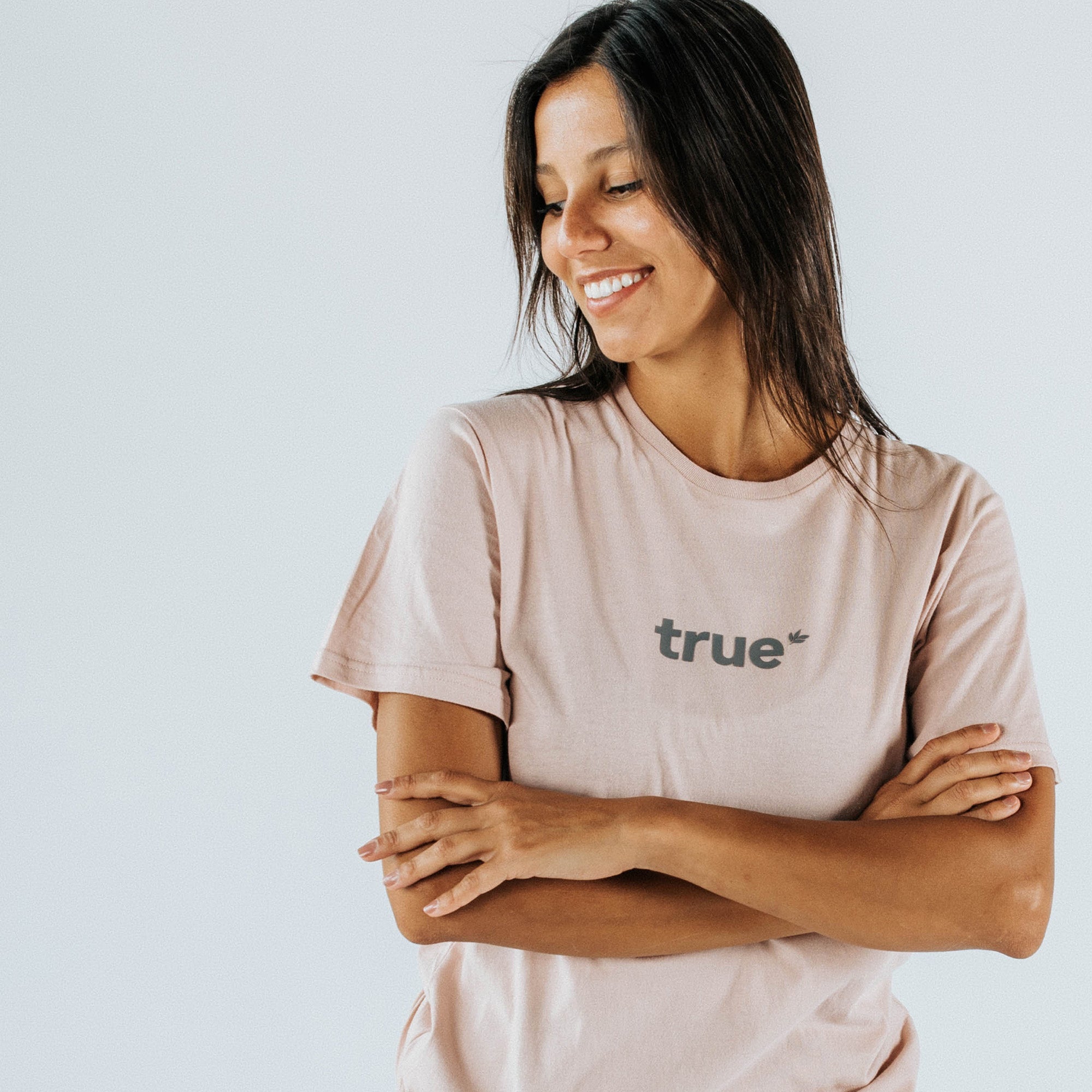 Smiling woman wearing blush-pink "true" logo women&