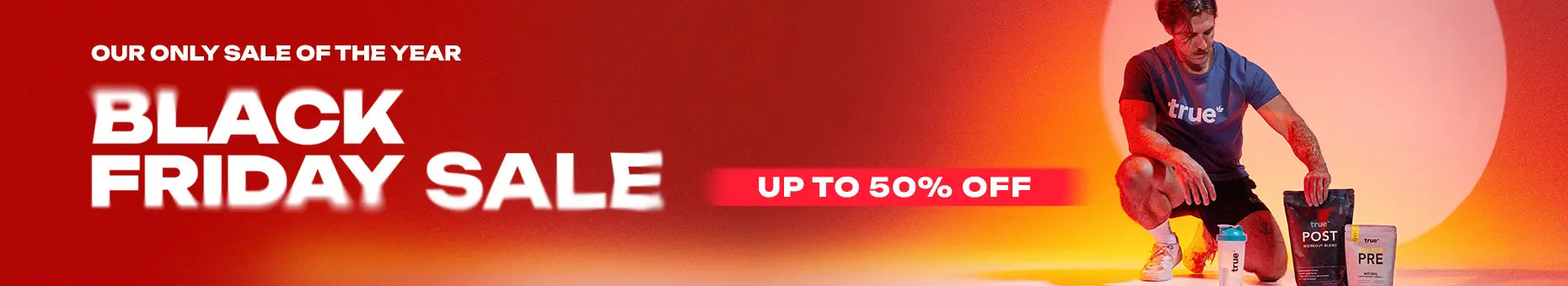 Black Friday sale banner: bold "Black Friday Sale" text and "Up to 50% off" with a male athlete kneeling beside True Protein branded pre- and post-workout supplement pouches and shaker bottle on orange-red background