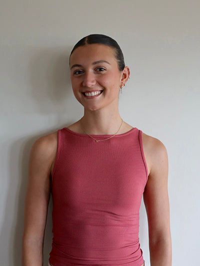 Woman wearing a pink sleeveless top against a plain background