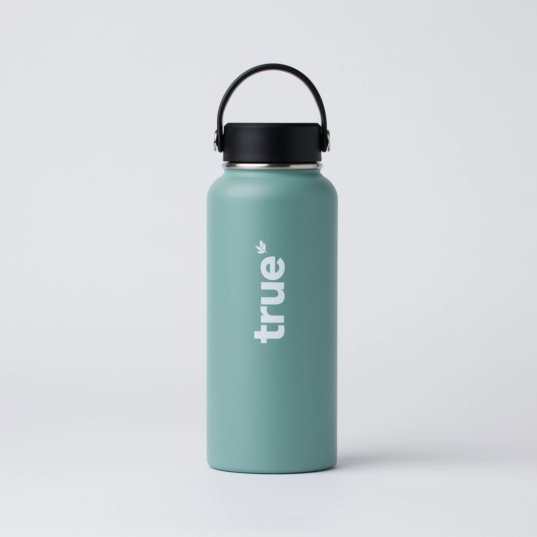 Sage green matte stainless steel insulated water bottle with black handle cap and vertical white &quot;true&quot; logo, product studio photo on white background — reusable travel bottle.