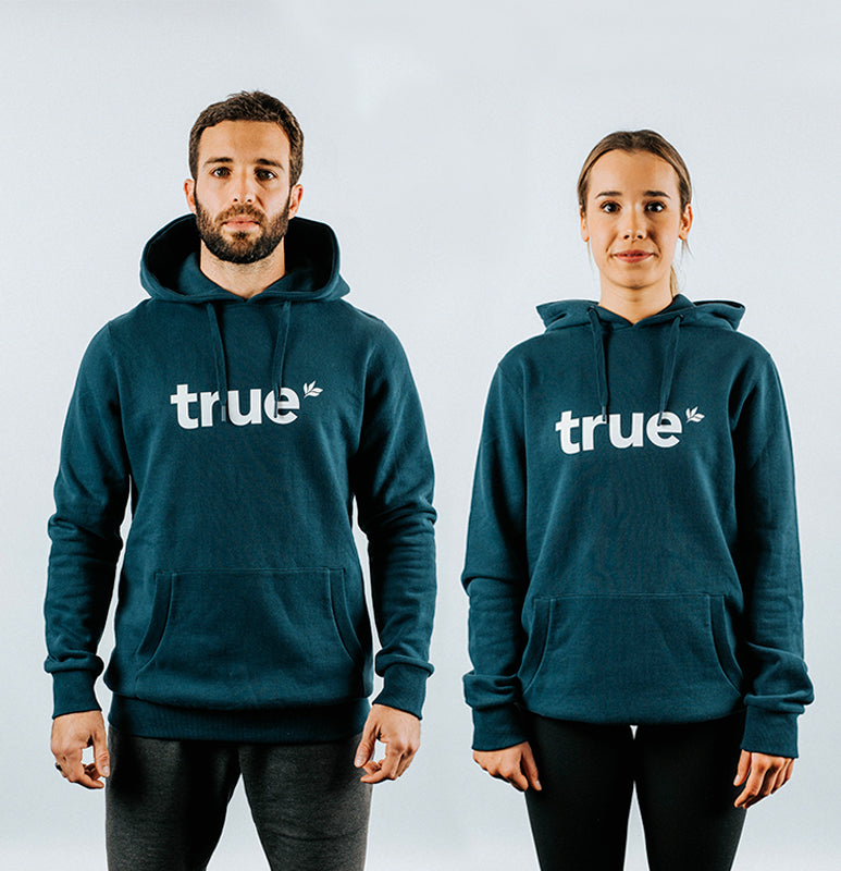 Navy unisex pullover hoodie with white &quot;true&quot; logo worn by male and female models, front view with drawstring hood and kangaroo pocket — product photo.